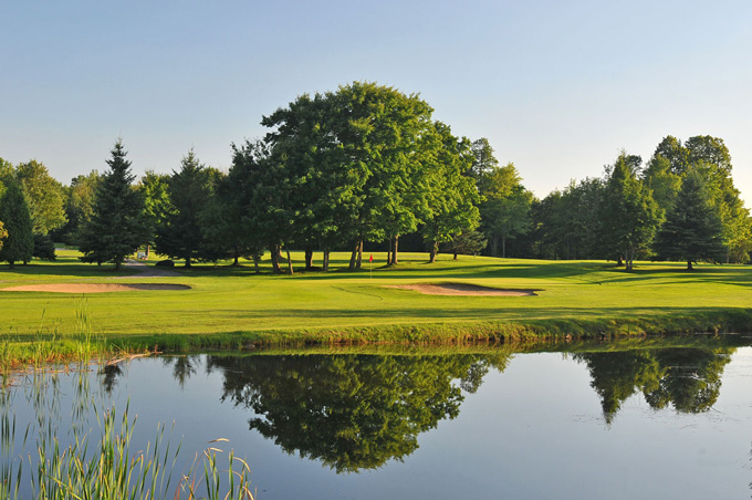 pond in front with a fairway and sand bunkers beyond pond